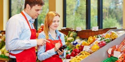 Žena a muž kontrolují ovoce a zeleninu v supermarketu