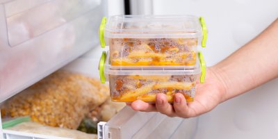 Člověk vkládá dvě krabičky, ve kterých jsou těstoviny s omáčkou, do mrazáku