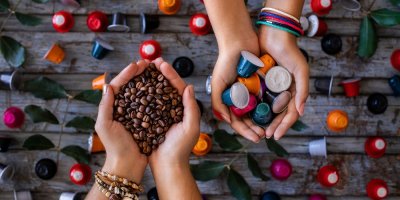 Ruce drží kapsle a zrnkovou kávu