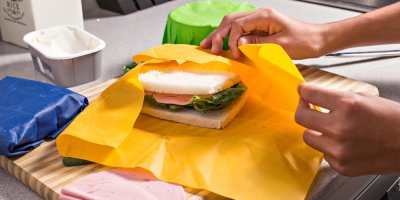 Ruce balí sandvič do voskového papíru