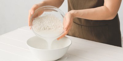 Žena slévá vodu z rýže do misky