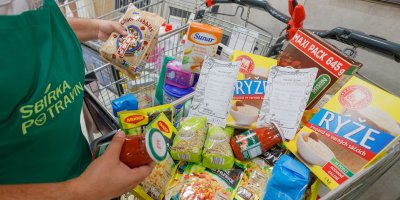 Dobrovolnice Sbírky potravin u nákupního vozíku plného trvanlivých potravin a surovin