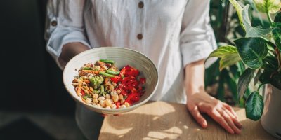 Žena drží v ruce misku se zeleninovým salátem 