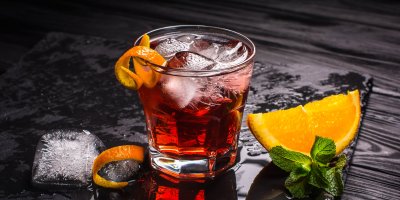 Sklenice koktejlu Negroni s ledem a pomerančem