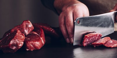 Člověk krájí hovězí maso na plátky