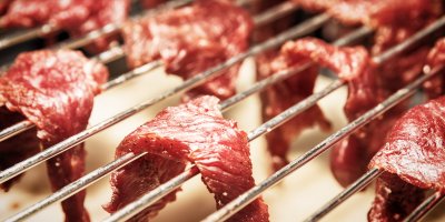 Kousky hovězího masa zavěšené na roštu v troubě