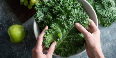 Ženské ruce dávají listy kadeřávku do misky