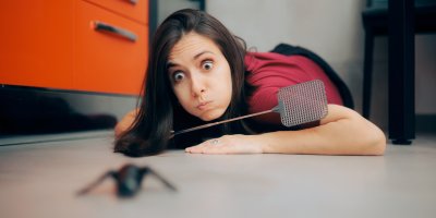 Žena loví pavouka plácačkou na mouchy