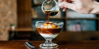 Člověk lije kávu do pohárku se  zmrzlinou