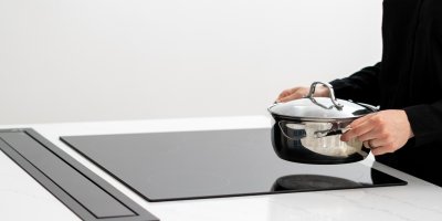 Žena dává hrnec na indukční desku