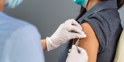 Lékař píchá ženě injekci do ramene