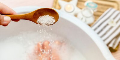 Člověk sype sůl do lavoru, ve kterém má nohy