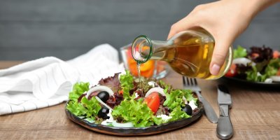 Žena lije jablečný ocet do salátu