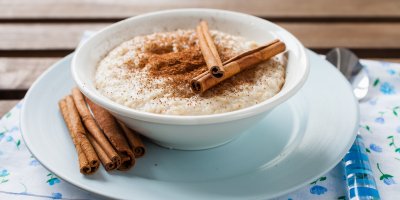 Ovesná kaše posypaná skořicí, na ní jsou položené i svitky celé skořice