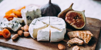 Prkénko, na němž je camembert a další druhy sýrů, fíky, sušené ovoce, oříšky a krekry