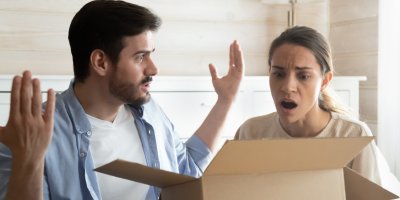 Žena se zklamaně dívá do krabice, muž vedle ní rozhazuje rukama