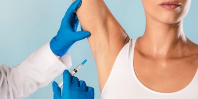 Lékař píchá ženě injekci do podpaží