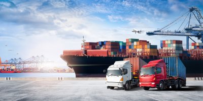 Kontejnerová doprava – plná nákladní loď a kamiony v přístavu