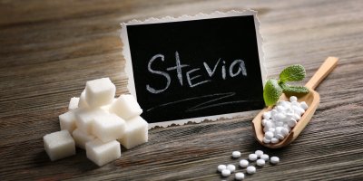 Cedulka s nápisem „Stevia“, kostky cukru a pilulky stévie
