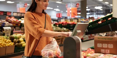 Žena v supermarketu váží jablka v opakovatelně použitelném sáčku