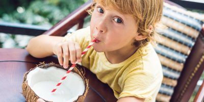 Malý kluk pije brčkem z rozpůleného kokosu