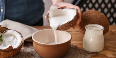 Žena lije kokosové mléko z kokosu do misky