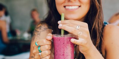 Žena se usmívá a drží růžové smoothie