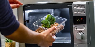 Muž vyndává jídlo v krabičce z mikrovlnky