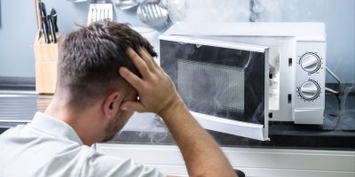 Muž stojící u hořící mikrovlnky