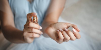 Žena si stříká parfém na zápěstí