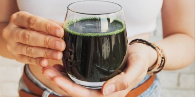 Žena drží skleničku s chlorelou