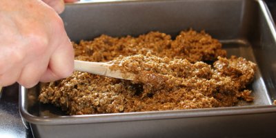 Člověk uhlazuje směs na flapjack v plechu