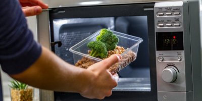 Ruce vkládají brokolici do mikrovlnky