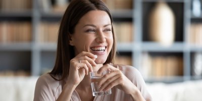 Žena drží v ruce tabletu a sklenici vody