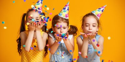 Trojice oslavujících dívek s papírovými třpytkami