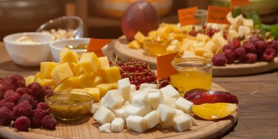 Různé druhy sýrů nakrájené na kostky, maliny, nektarinky, rybíz, dipy v mističkách