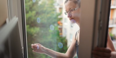 Žena lepí UV samolepky na prosklené dveře