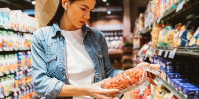 Žena si v obchodě prohlíží složení na čočkových těstovinách