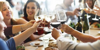 Přátelé si ťukají sklenicemi u stolu