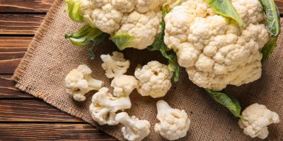 Dva celé květáky a malé kousky květáku na jutové podložce