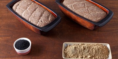 Dva bochníky domácího chleba ze žaludové mouky a misky s žaludovou moukou a kořením