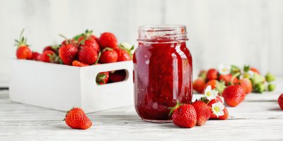 Domácí jahodová marmeláda ve sklenici, čerstvé jahody v bedýnce