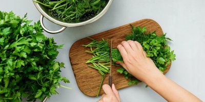 Ruce krájí petrželku a kopr