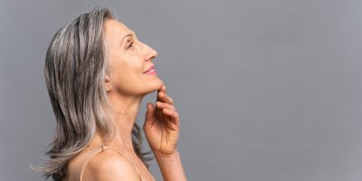 Starší žena si drží bradu a usmívá se