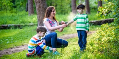 Maminka stříká děti v lese repelentem