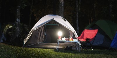 Stan, stolek, kempingová židle a rozsvícená svítilna