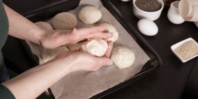 Ruce tvoří bulky z těsta a pokládají je na plech