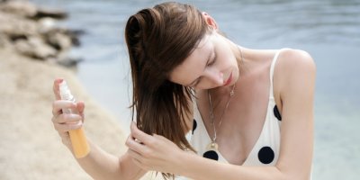 Žena si stříká kondicionér do vlasů