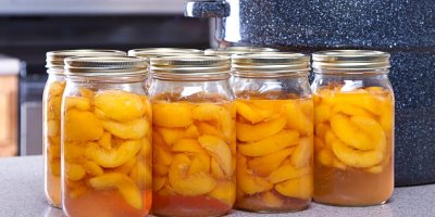 Zavařovací sklenice plné ovoce na kuchyňské lince u zavařovacího hrnce 