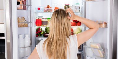 Žena prohlížející si plnou ledničku